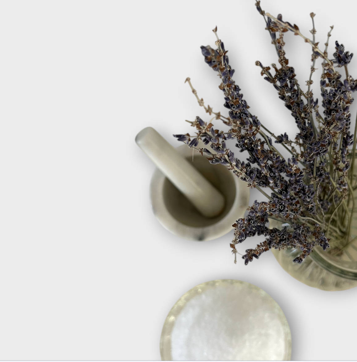 Mortar and pestle with a glass container of dried lavender on a white background