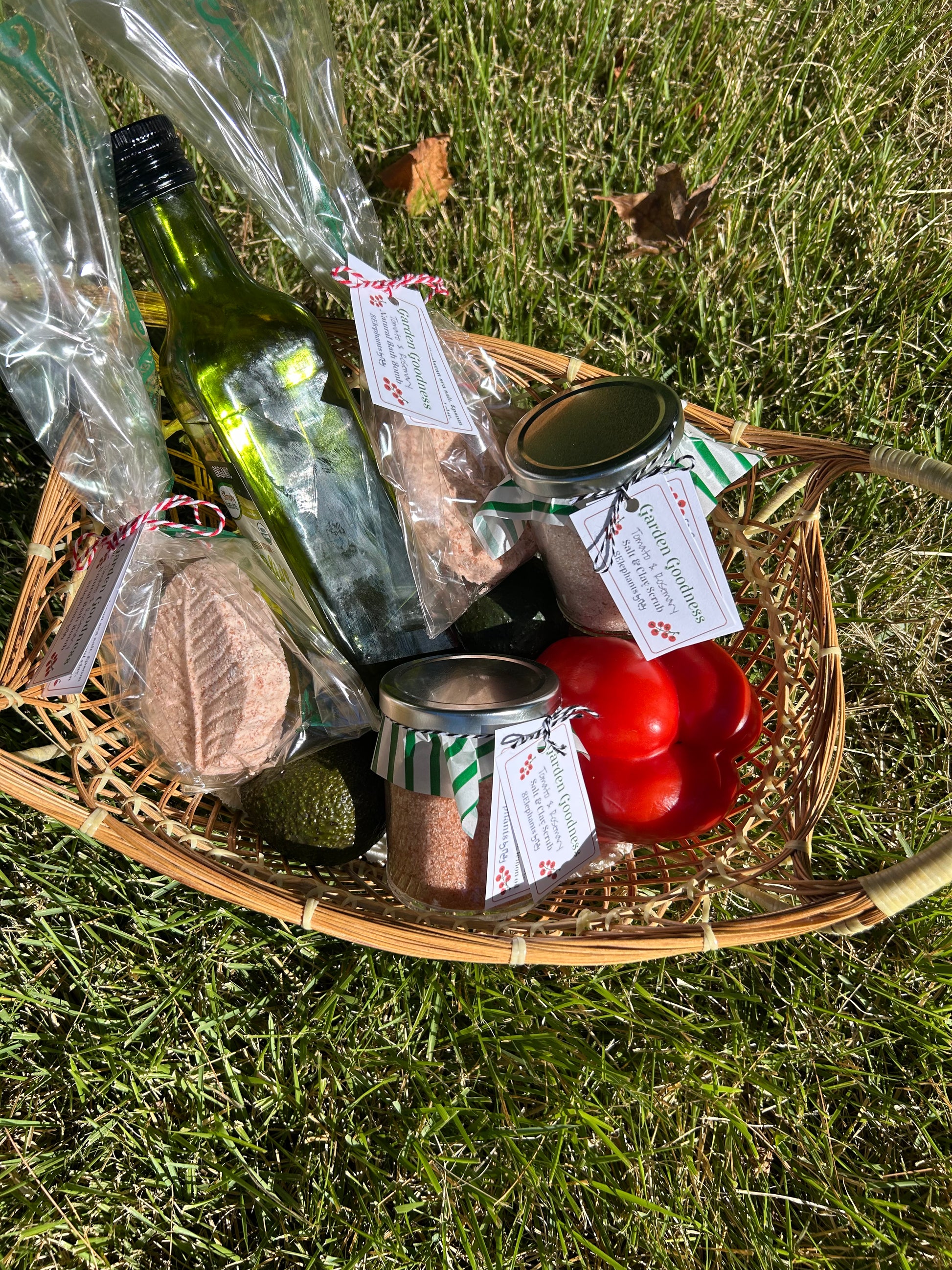Wicker basket with food items including bottles and jars on grass